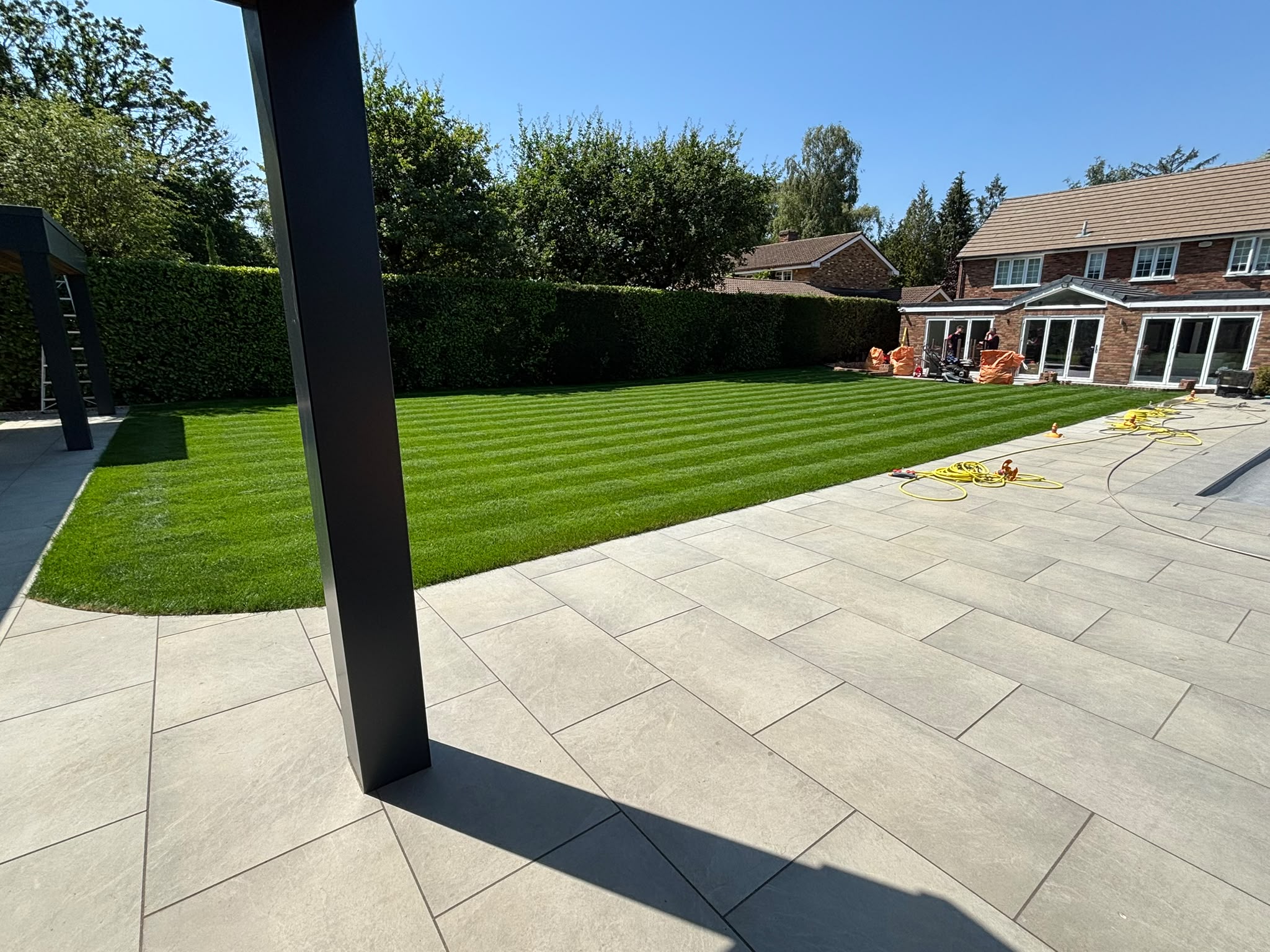 Finished patio paving beside a striped lawn
